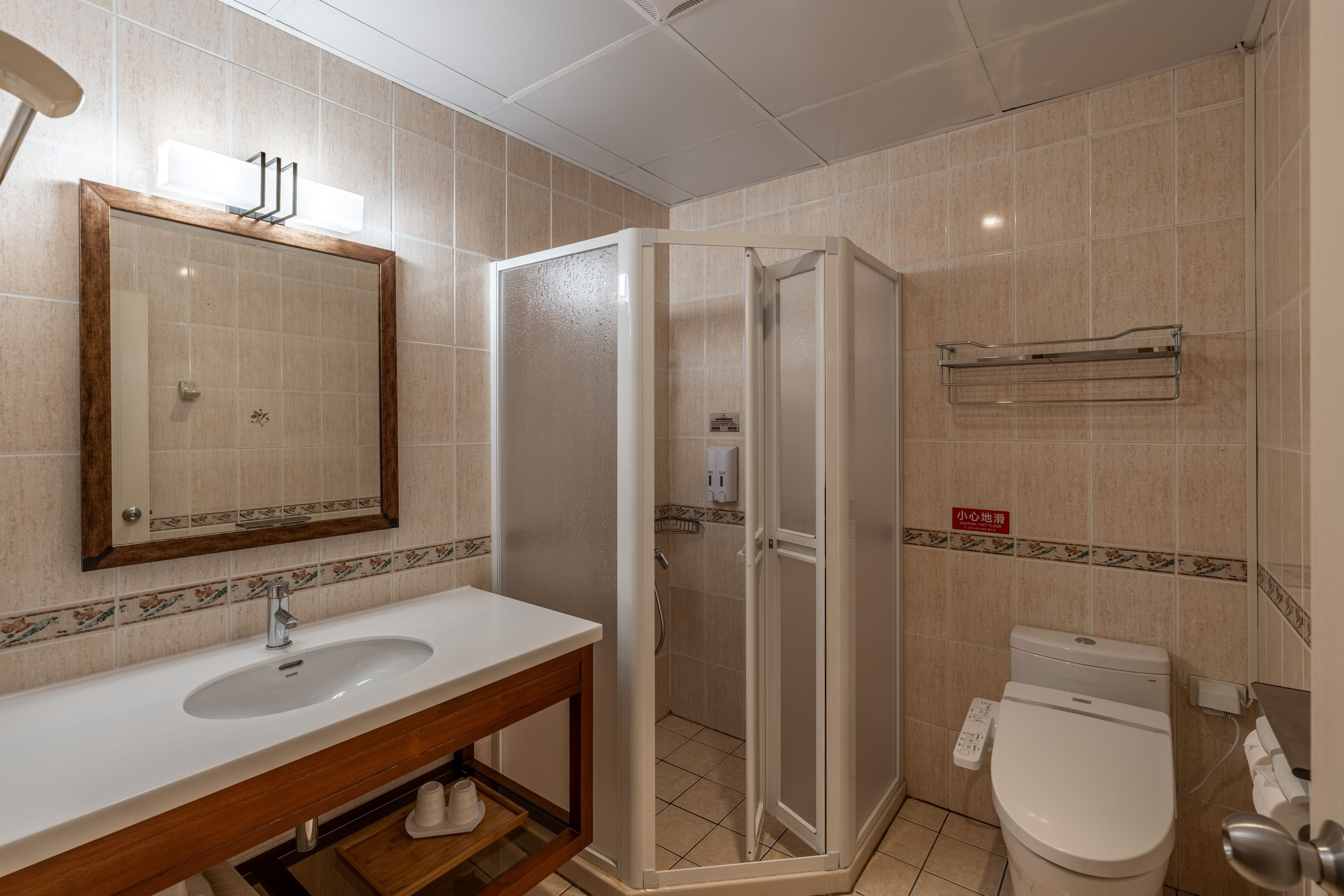 A bathroom with a white sink, a mirror, a shower enclosure, and a toilet.