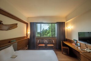 A hotel room with a bed, a desk with a telephone, a television, and a window with curtains. - Ginkgo Hotel (Lugu)