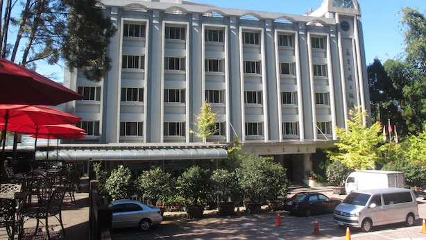 Un hotel de varios pisos con fachada simétrica, amplias ventanas y una entrada central.
