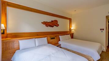 Quarto de hotel com duas camas, cabeceiras de madeira, uma obra de arte na parede e uma mesinha de cabeceira com abajur.