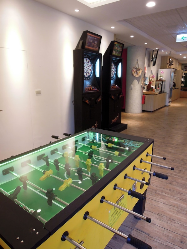 Una mesa de fútbol de mesa en una sala con juegos de arcade y un dardo.