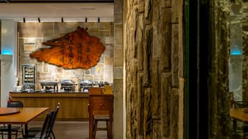 A restaurant interior with a stone wall, a wooden counter, and a large decorative piece.