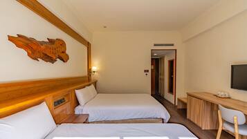 A hotel room with two beds, a desk, a chair, and a television.