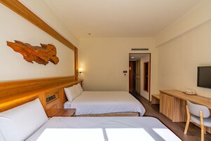 Una habitación de hotel con dos camas, un escritorio, una silla y un televisor.