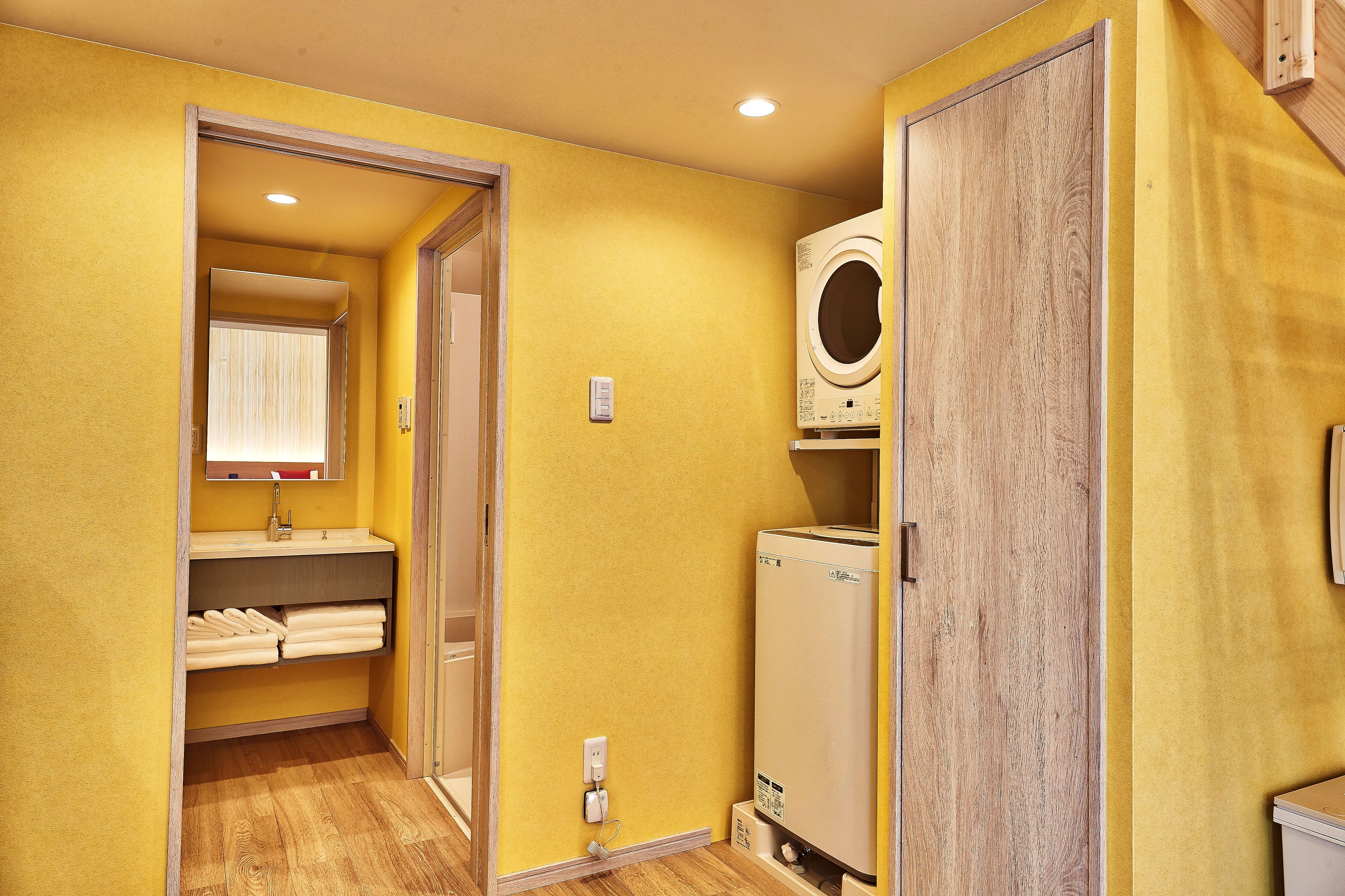 A compact bathroom with a wooden floor, a built-in sink, and a white washing machine.