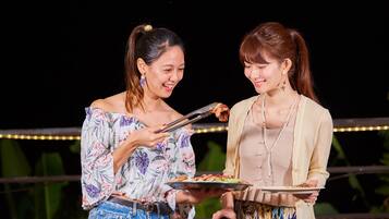 Two people holding plates of food, possibly at an outdoor event or gathering.