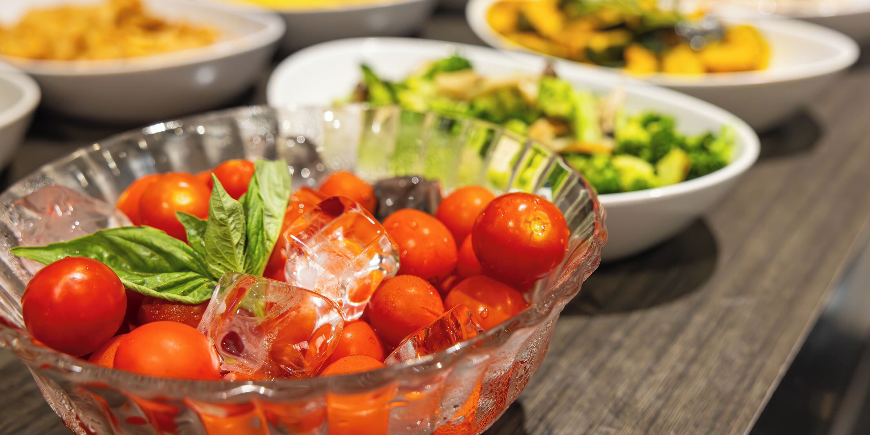 A glass bowl filled with cherry tomatoes and ice cubes.