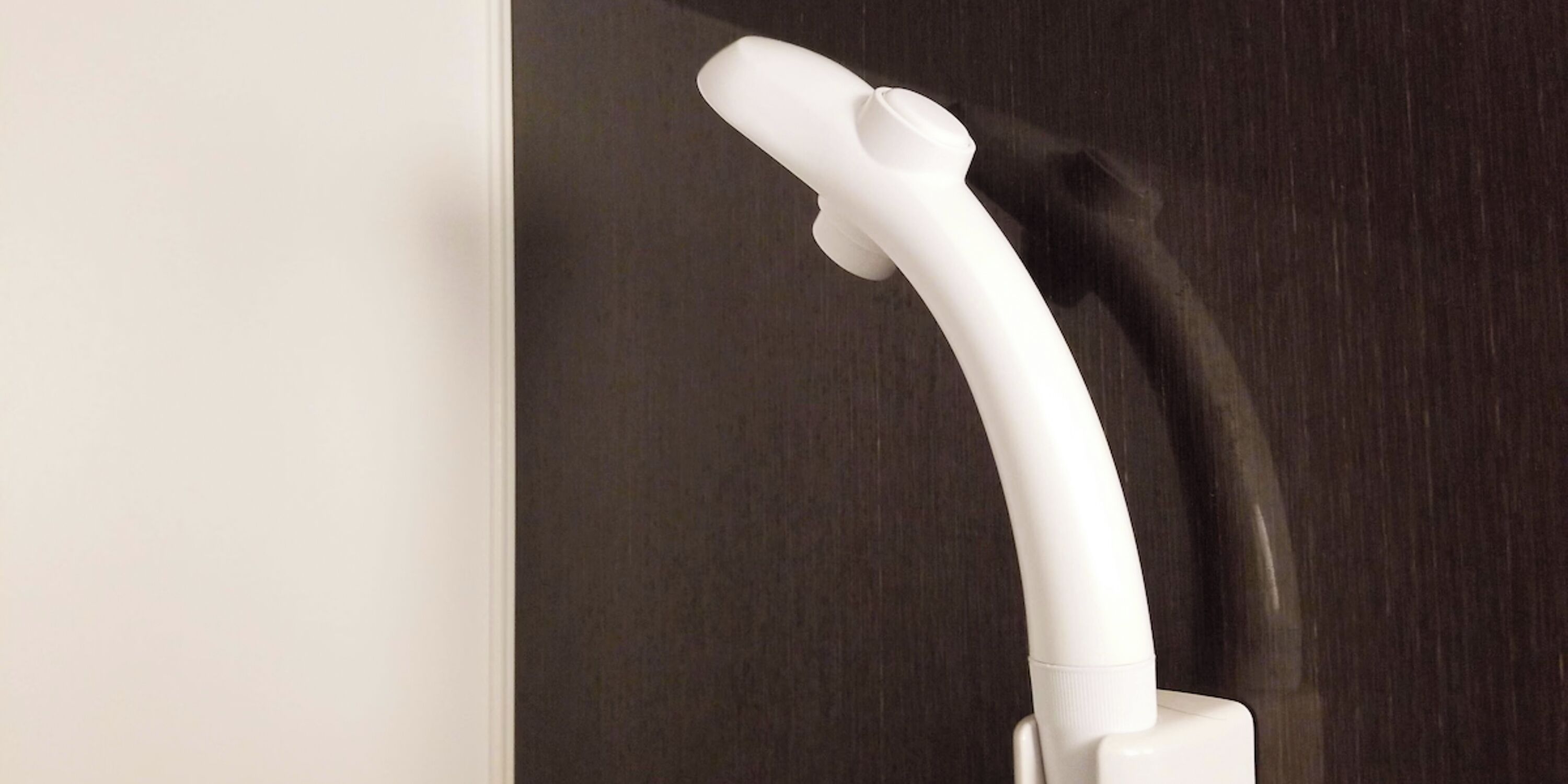 A white vacuum cleaner with a long hose against a dark background.