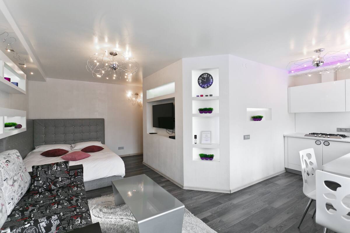 Un espacio habitable moderno y funcional, con cama, sofá y kitchenette.