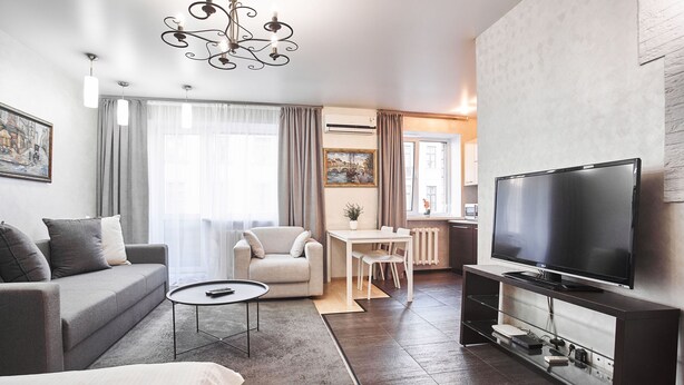 Ein modernes Wohnzimmer mit einer Couch, einem Couchtisch, einem Fernseher und einem Essbereich mit Tisch und Stühlen.