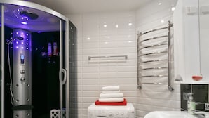Ein modernes Badezimmer mit einer gläsernen Duschkabine, einer integrierten Waschmaschine und einem weißen Waschbecken.