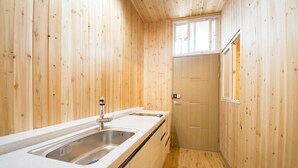 Una cocina pequeña con paredes de madera, un lavamanos y una ventana.
