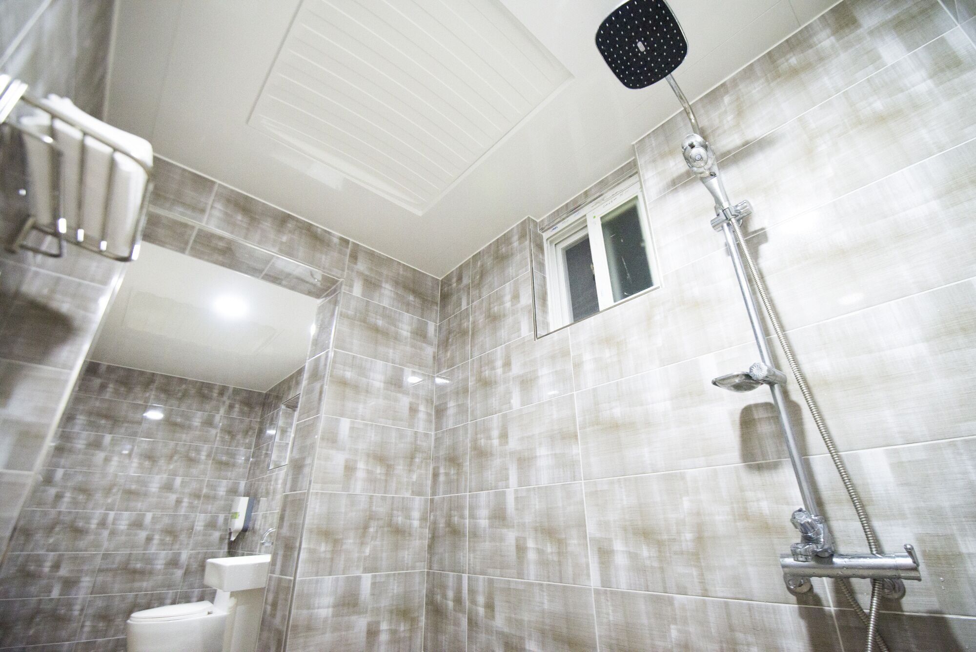 A bathroom with a shower, a toilet, and a window.