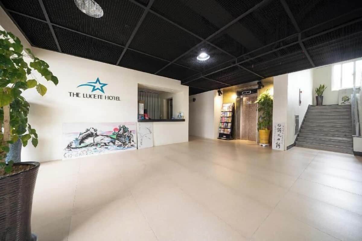 Una recepción de hotel con diseño moderno, un logotipo con una estrella y una escalera que conduce a otro piso.