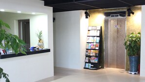 A reception area with a counter, a magazine rack, and an elevator. - The Lucete Hotel (Seogwipo)