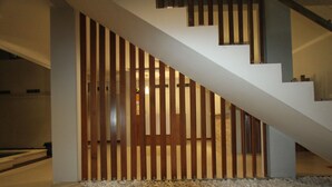 A modern staircase with a wooden railing and a white wall. - Tom Guest House (Kuta)
