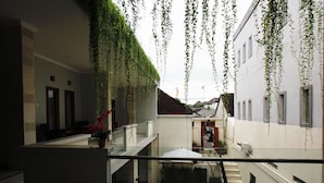A multi-level building with hanging plants, a staircase, and a glass railing. - Tom Guest House (Kuta)