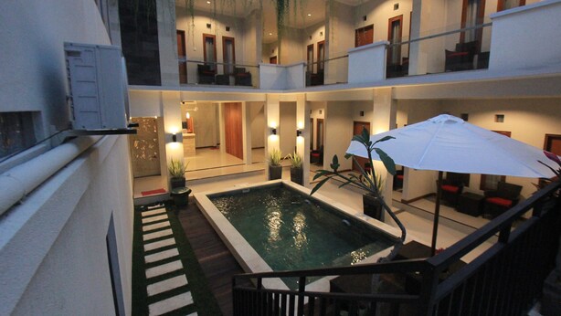 A multi-level indoor swimming pool area with multiple balconies, staircases, and seating areas. - Tom Guest House (Kuta)
