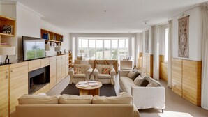 A spacious living room with a fireplace, comfortable seating, and large windows offering a view of the outdoors. - Logis DE Valandraud (Saint-Etienne-De-Lisse)