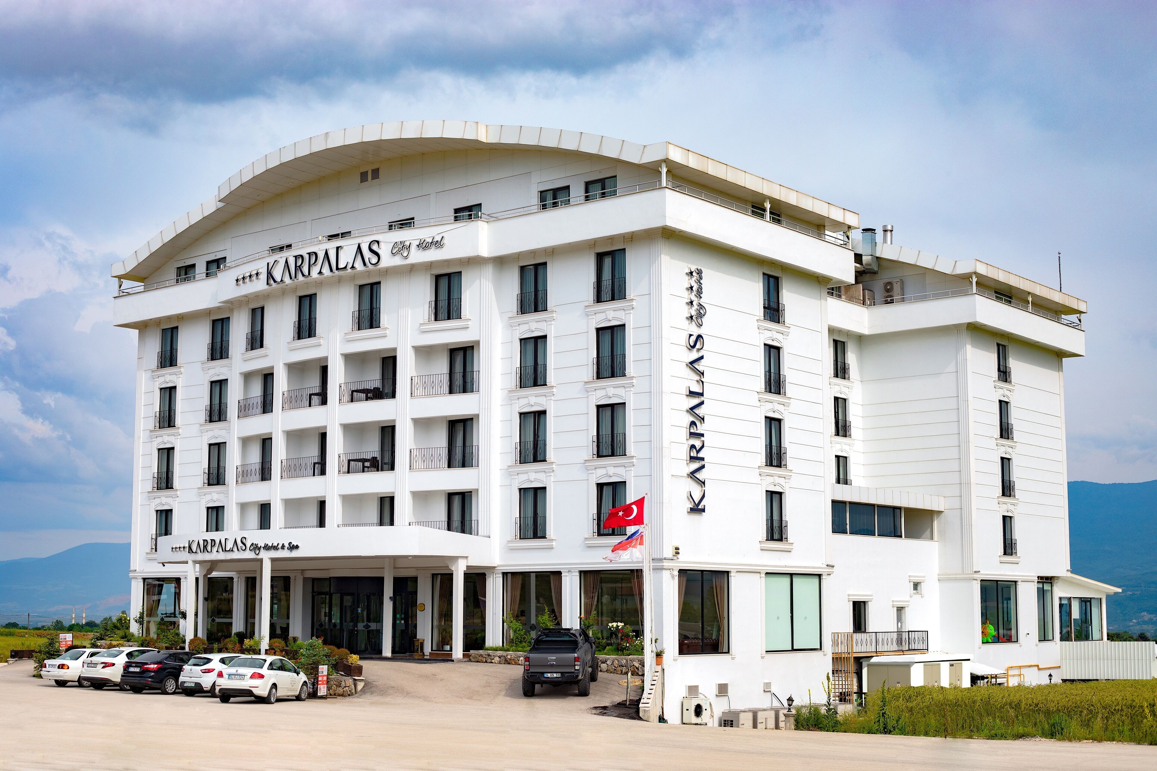 A multi-story hotel with a white facade, balconies, and a flag.