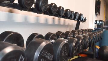 Estante con discos de pesas y mancuernas en un gimnasio.