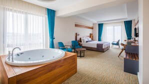 Una habitación de hotel con una bañera grande, una cama, un escritorio y una silla.