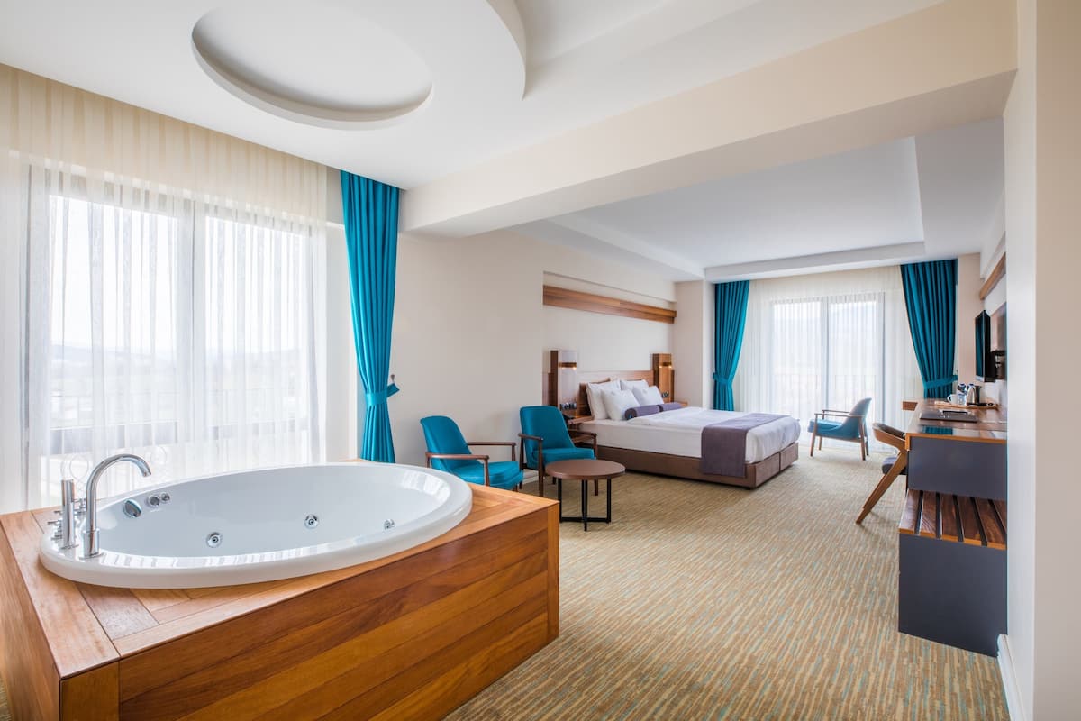 Une chambre d’hôtel avec une grande baignoire, un lit, un bureau et une chaise.