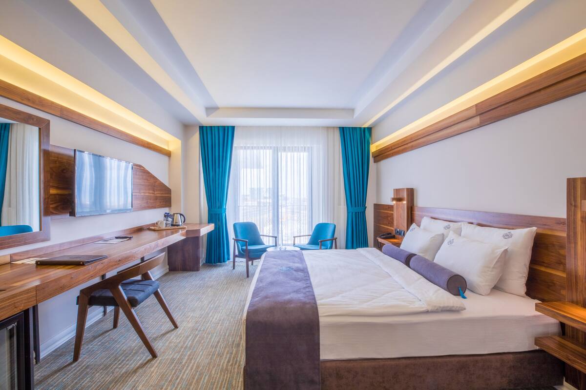 Une chambre d’hôtel équipée d’un lit, d’un bureau, de chaises et d’un téléviseur.