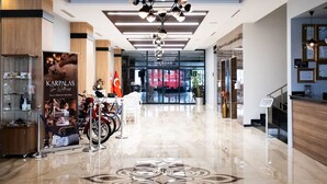 Un vestíbulo de hotel con un piso de mármol pulido, un candelabro central y un letrero del spa Karpalás.