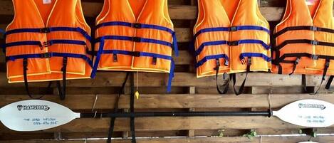 Chalecos salvavidas naranja colgados en una pared de madera con la información de contacto para 'The Lord Nelson' mostrada debajo.