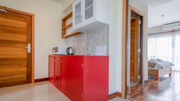 A modern kitchen with red cabinets, a microwave, and a coffee maker.