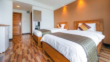 A hotel room with two wooden beds, a small kitchenette, and a wooden floor.