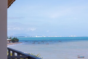 Vista costera con barcos en el agua, una playa y edificios a lo lejos.