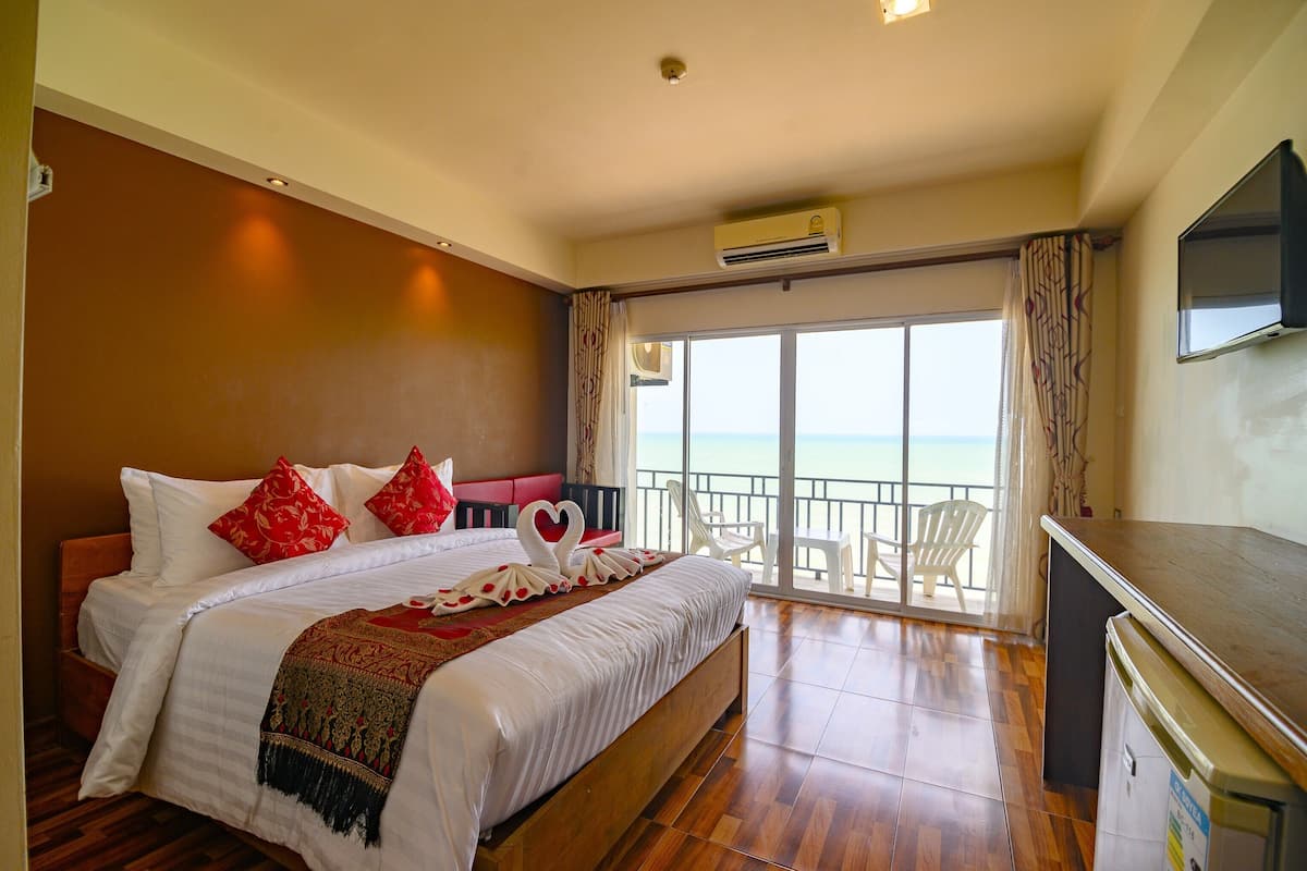 A hotel room with a large bed, a balcony with a view, and a television.