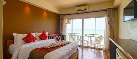Una habitación de hotel con una cama grande, un balcón con vistas y un televisor.