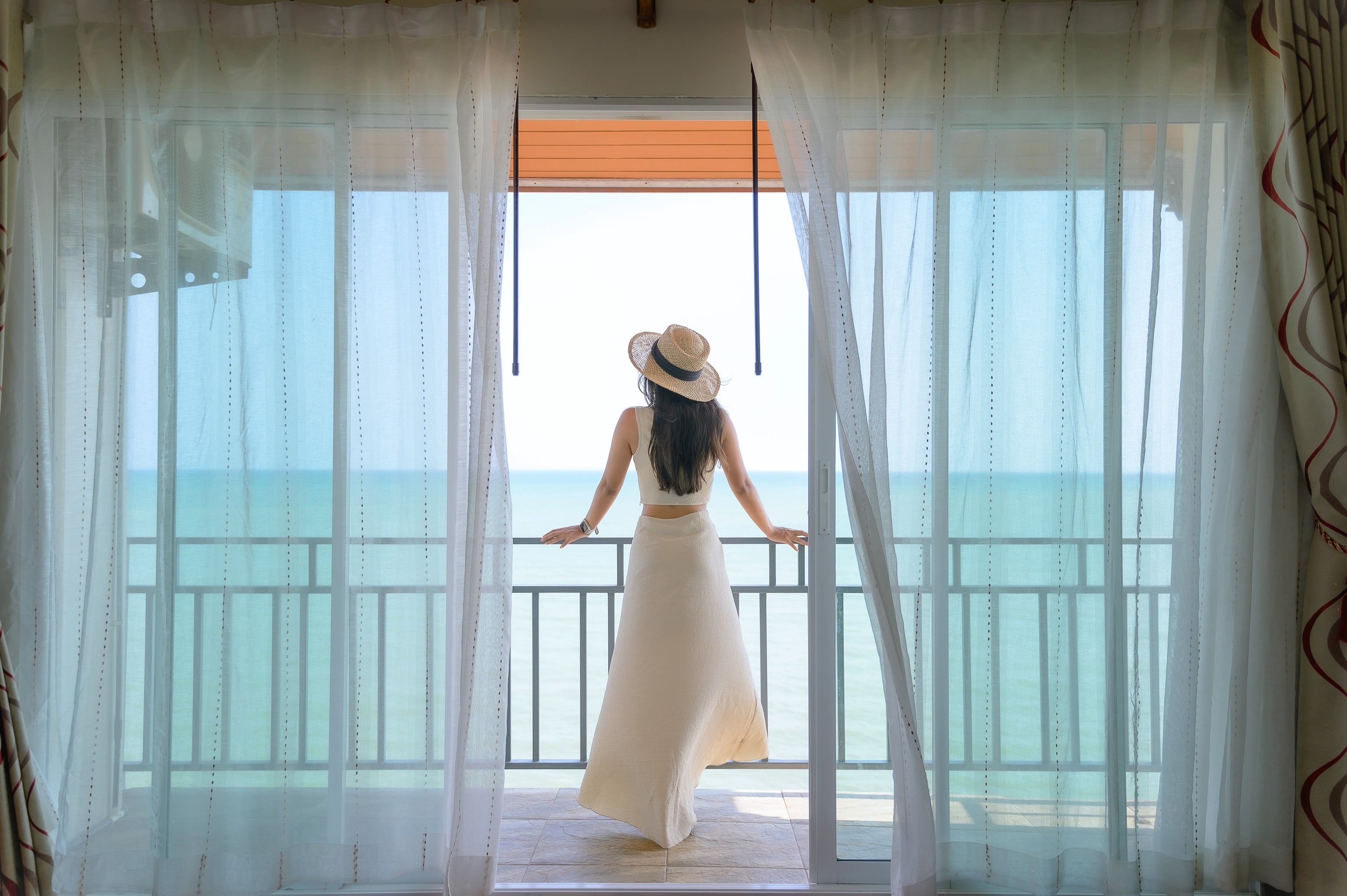 Quarto com vista para o mar através de cortinas finas.