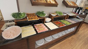 Un bufé con diferentes opciones de comida, incluyendo pan, ensaladas y carnes.