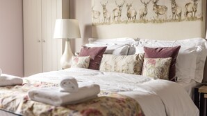 A neatly made bed with floral bedding, a white headboard, and decorative pillows. - Plum and Partridge Inn (York)