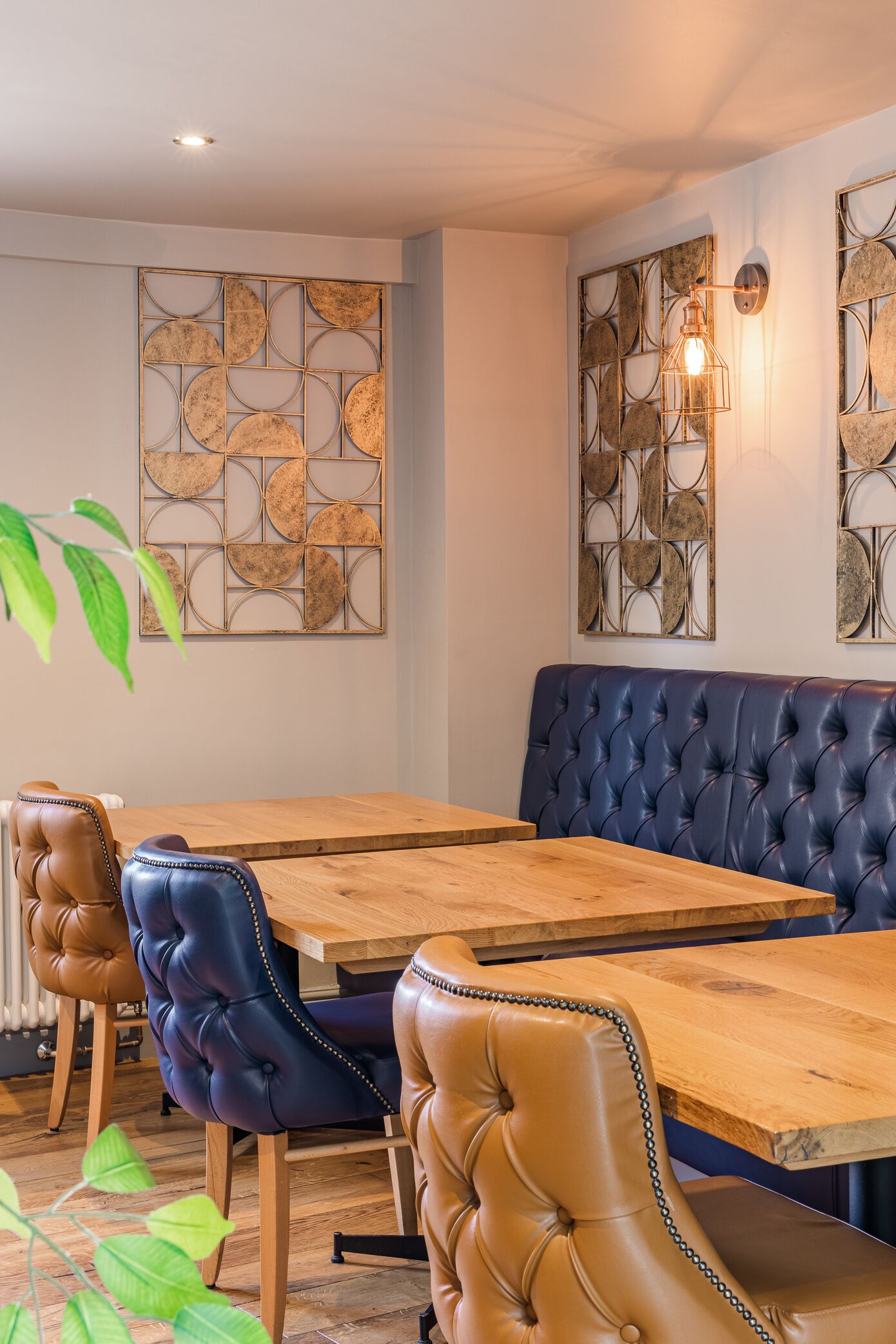 A dining area with a wooden table and leather chairs, a blue upholstered bench, and decorative wall art.