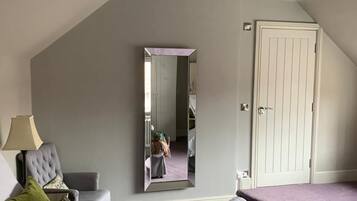 A bedroom with a large bed, a chair, a mirror, and a door.