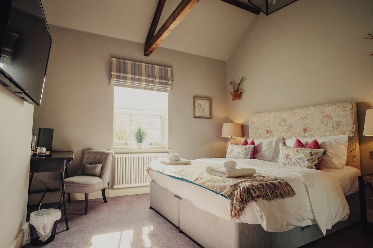 A bedroom with a bed, a chair, a desk, a radiator, and a window.