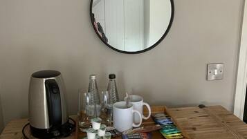 A wooden chest with a kettle, glasses, and a tray of snacks.