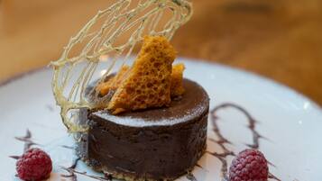 Un postre con base de chocolate, decoración de frambuesas y una red de azúcar decorativa.