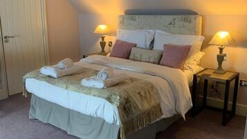A bedroom with a bed, two bedside lamps, a door, and a carpeted floor.