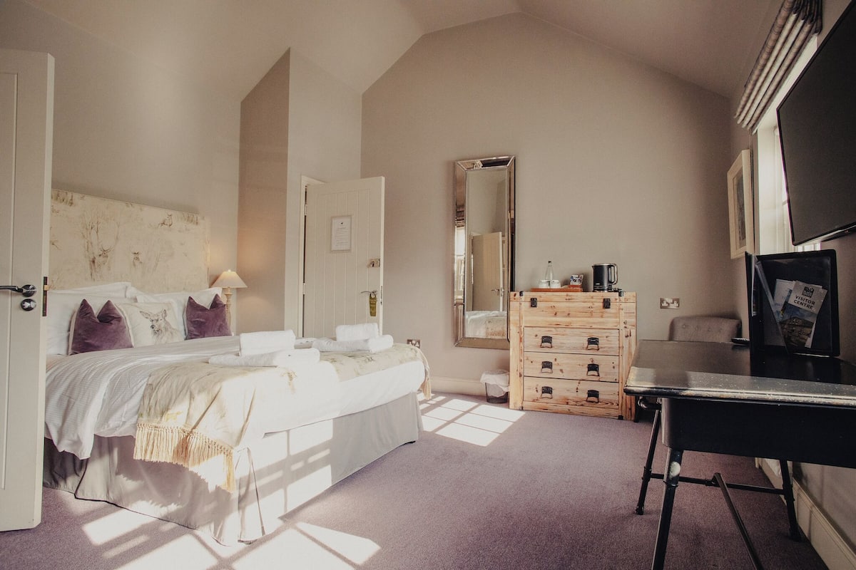 A bedroom with a bed, dresser, mirror, and a desk.