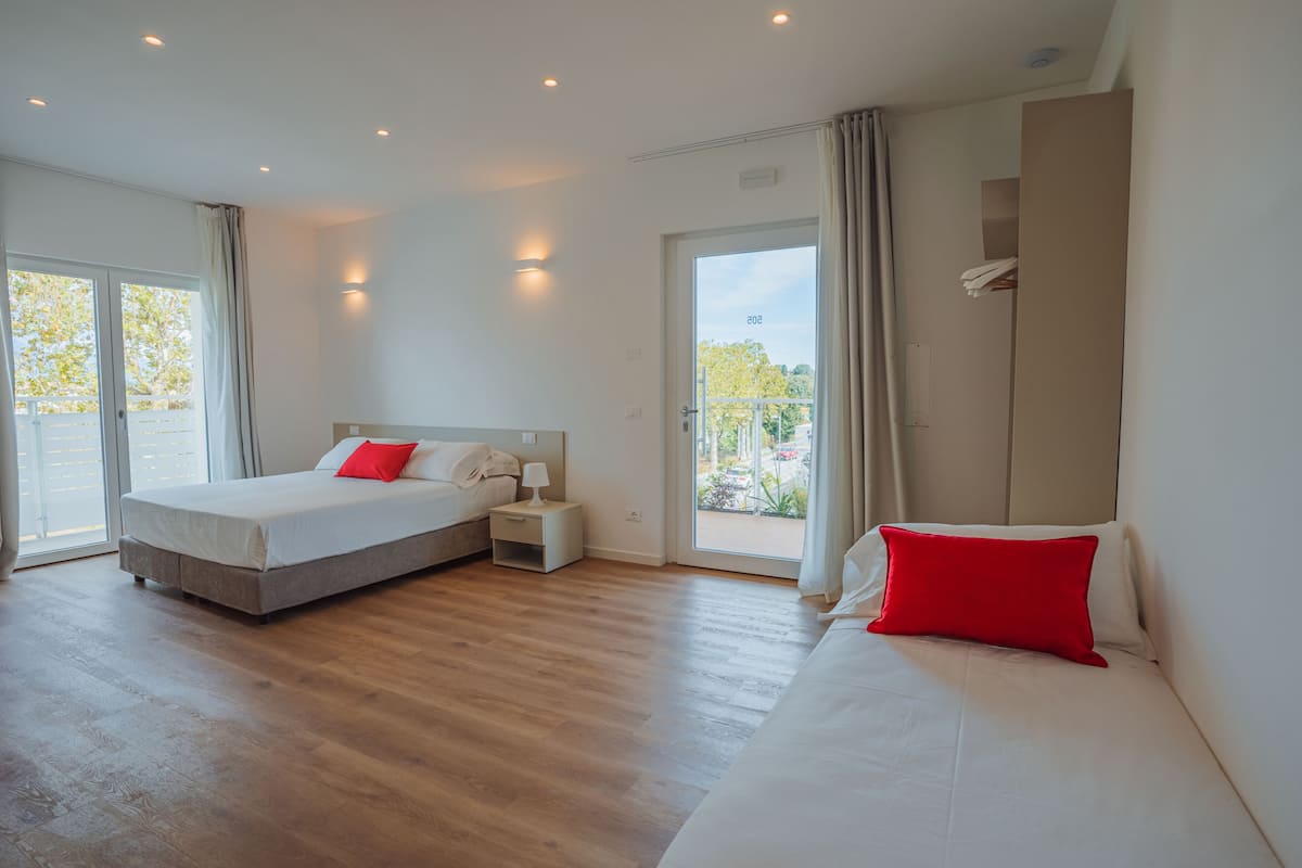 A modern hotel room with a large bed, a smaller bed, a nightstand, and a wardrobe.
