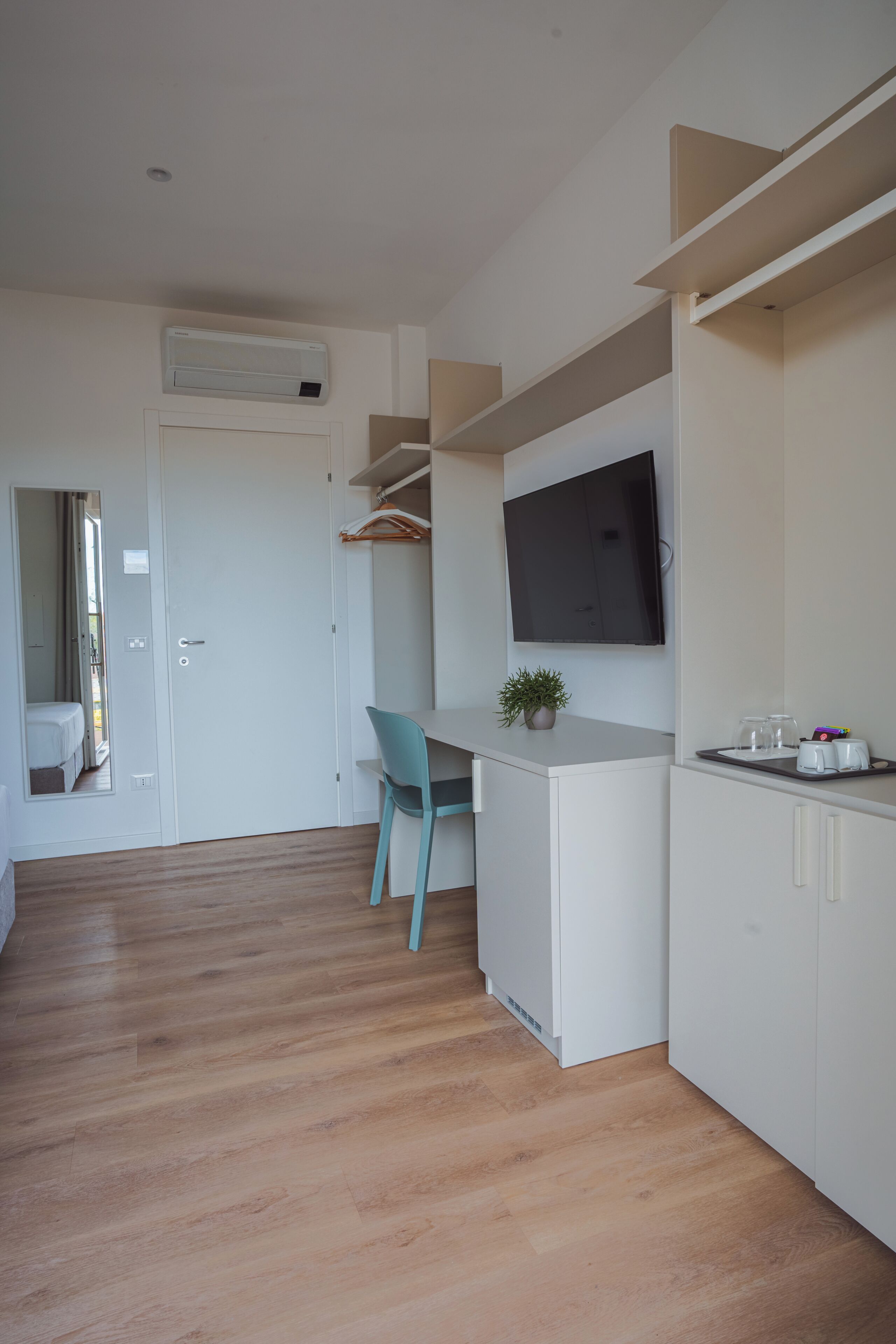 A modern kitchen with a built-in TV, wooden flooring, and a blue chair.