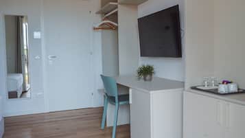 A modern kitchen with a built-in TV, wooden flooring, and a blue chair.