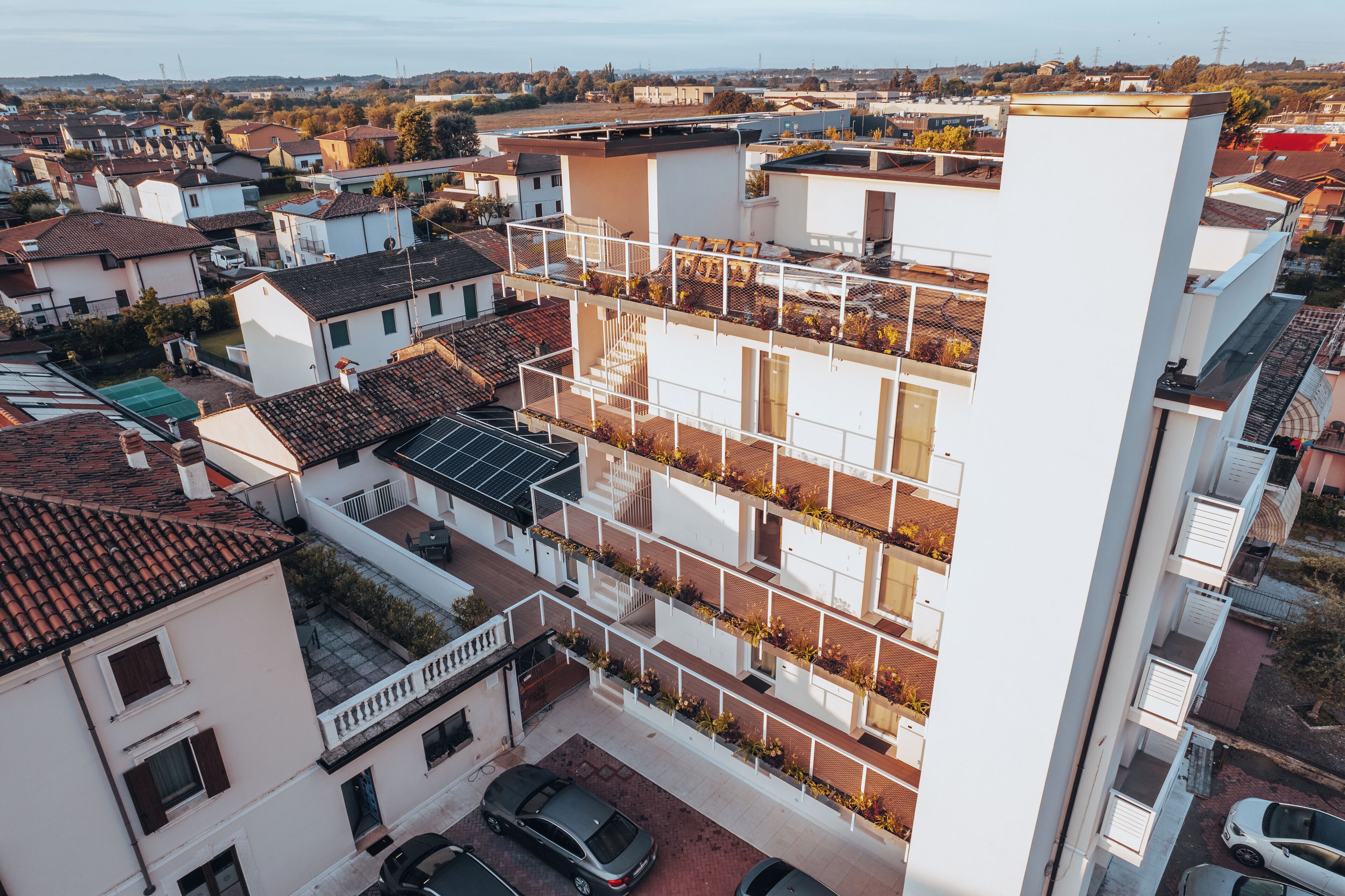 A multi-story residential building with balconies, a carport, and a solar panel on the roof.