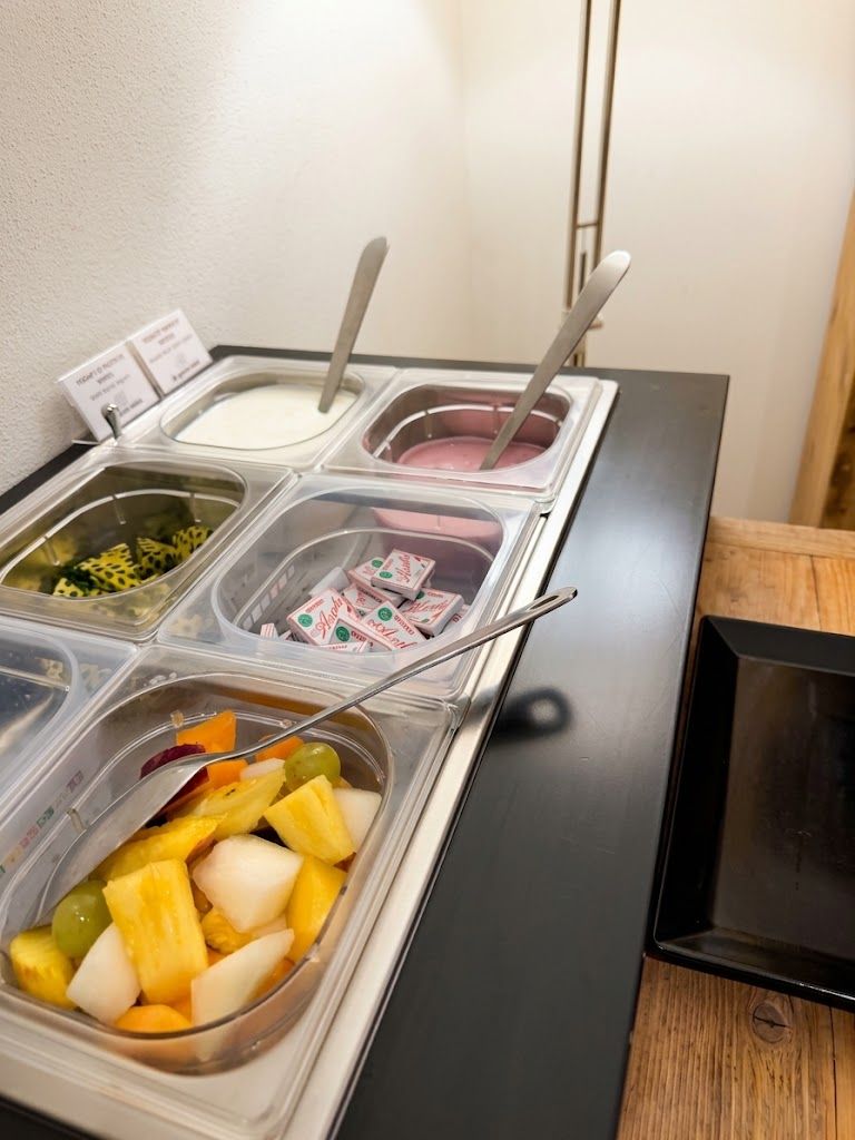 A self-serve beverage station with multiple containers, including a selection of juices and a yogurt drink.